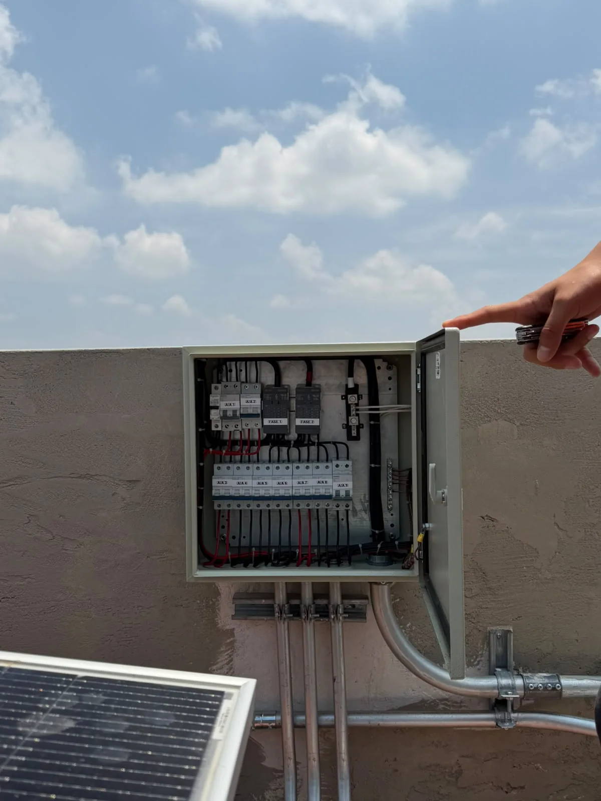 Gabinete eléctrico abierto con protecciones y conductores conectados a canalizaciones metálicas.